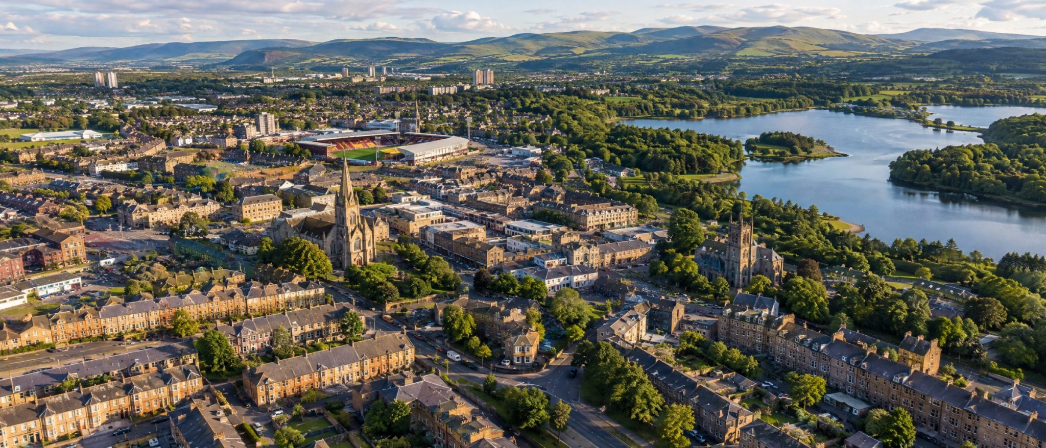 Aerial view of Motherwell with sandstone streets, church spires and Strathclyde Loch