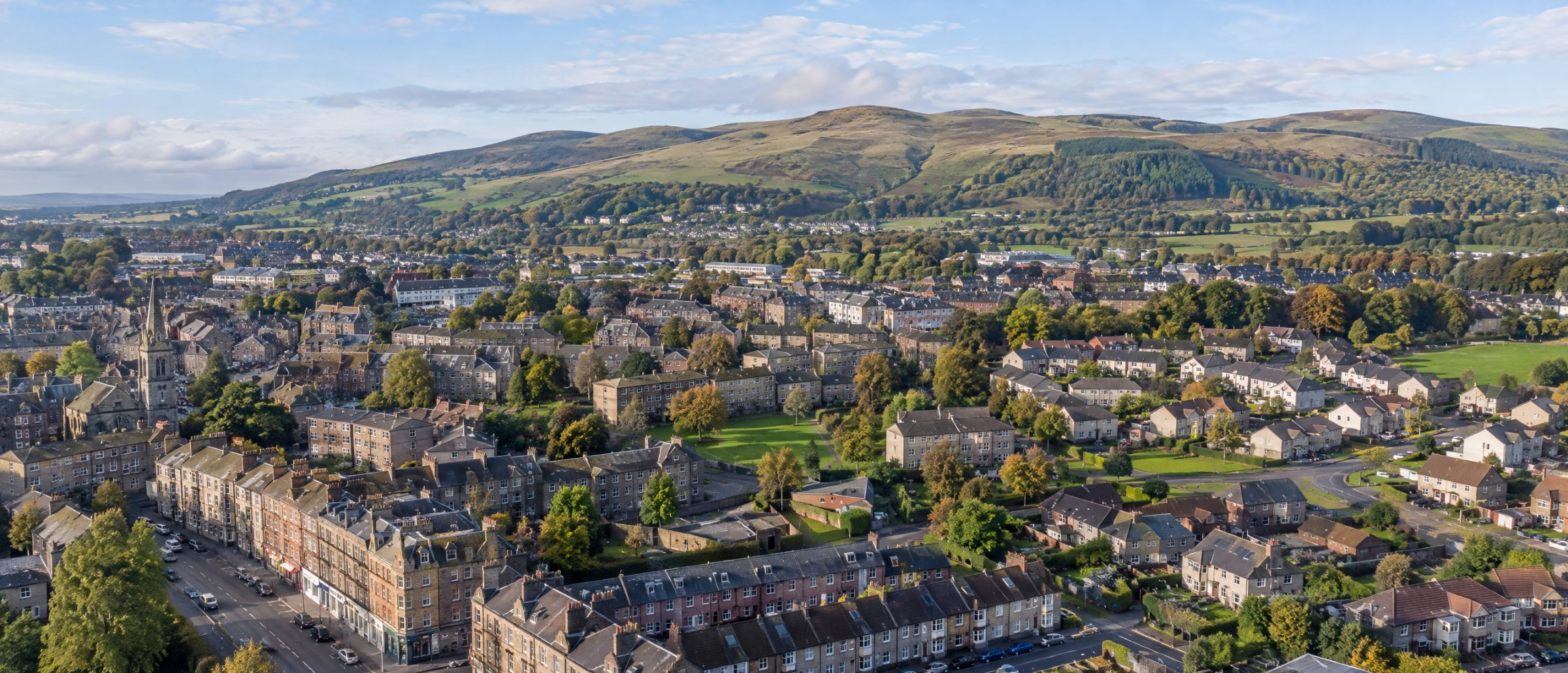 Aerial view of Barrhead with homes and green space, and the Fereneze Braes behind