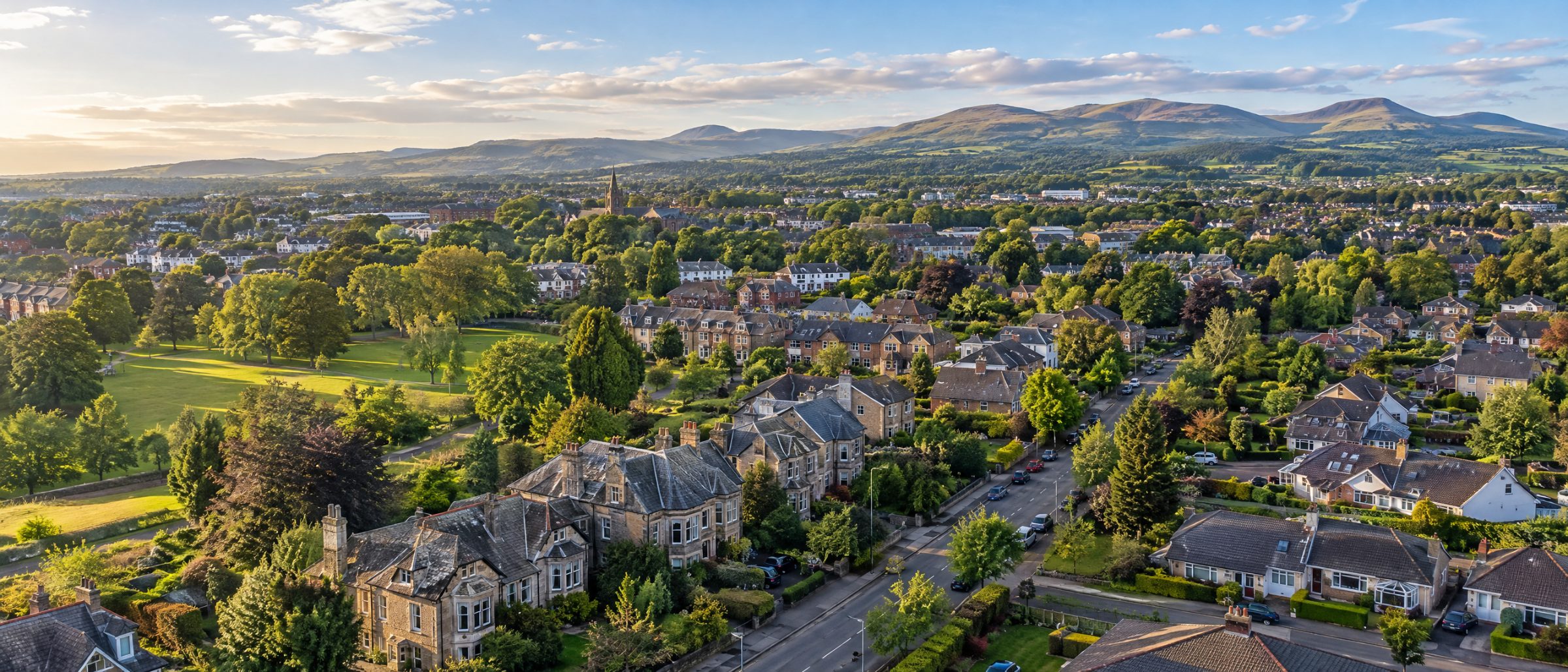 Aerial view of Bishopbriggs with family homes, gardens and parkland, and the Campsie Fells on the horizon