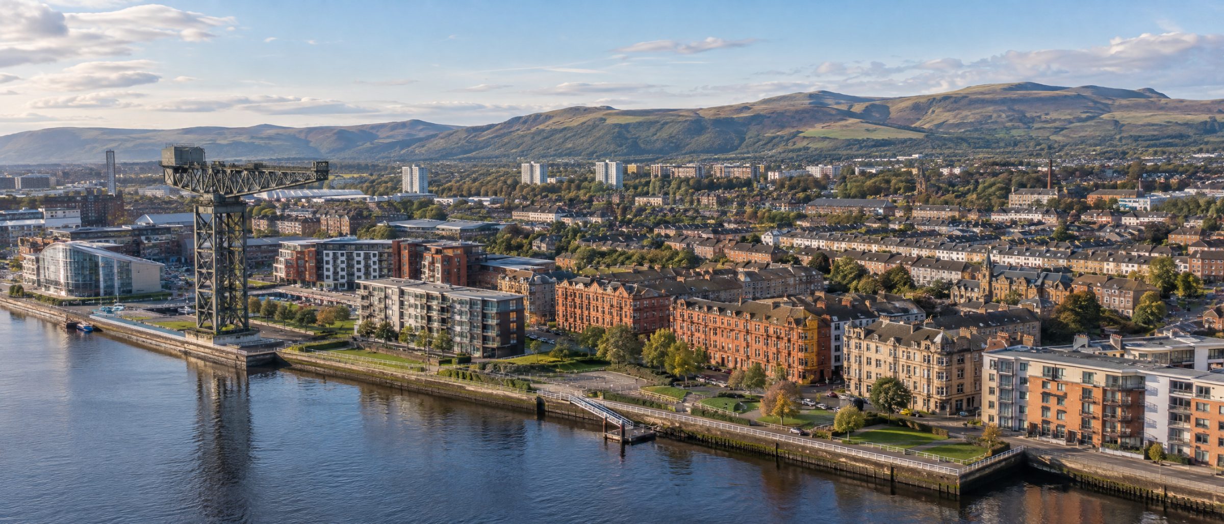 Aerial view of Clydebank with the Titan Crane on the River Clyde, tenements and homes, and the Kilpatrick Hills behind