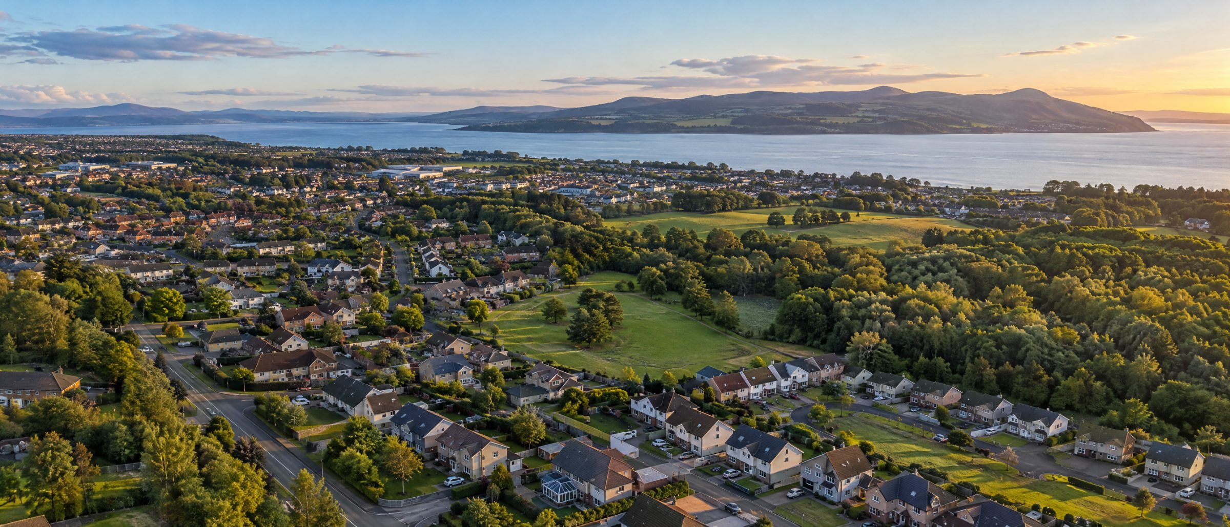 Aerial view of family homes and green space in Culloden, Inverness, with the Moray Firth beyond