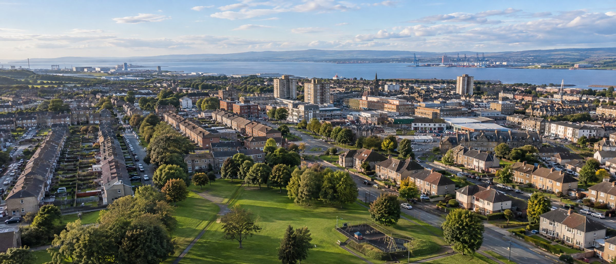 Aerial view of homes and parkland in Grangemouth, with the Firth of Forth and the port beyond