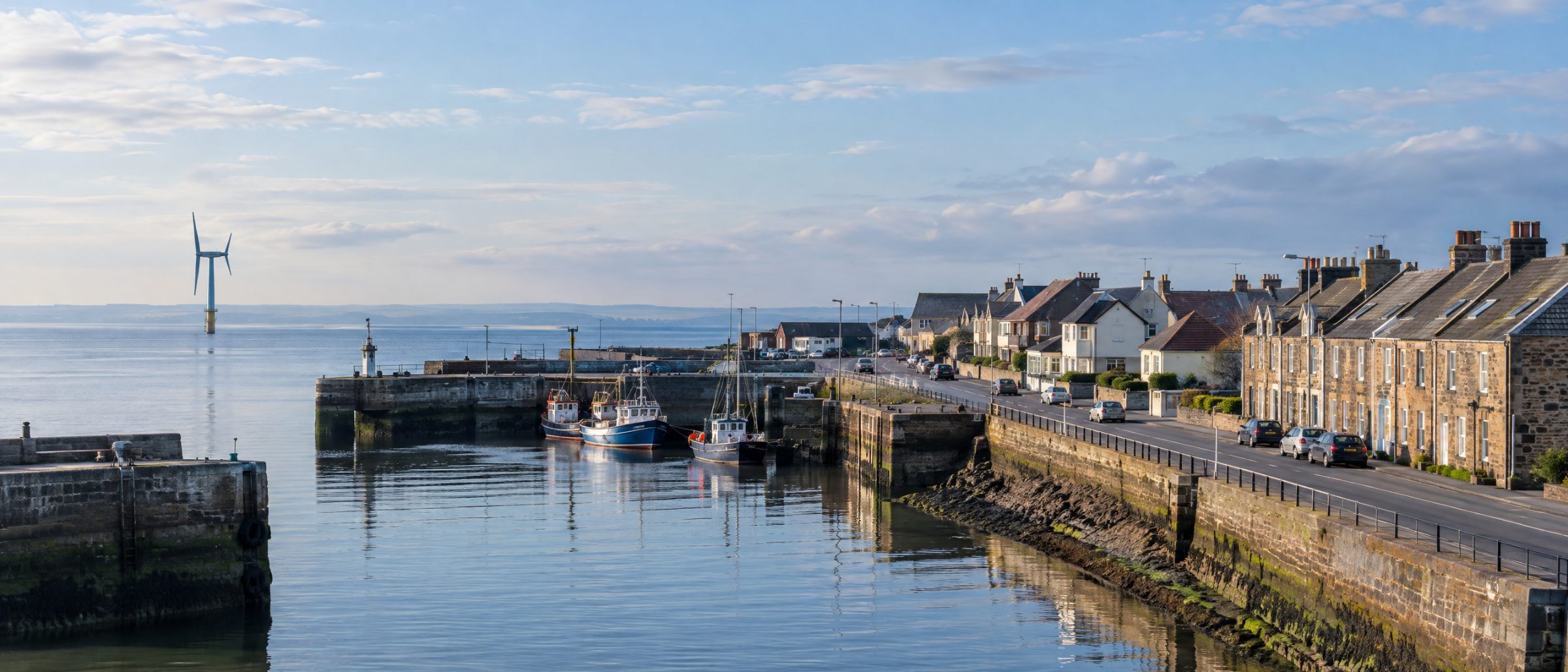 Methil harbour with stone terraced houses and the offshore wind turbine in the Firth of Forth
