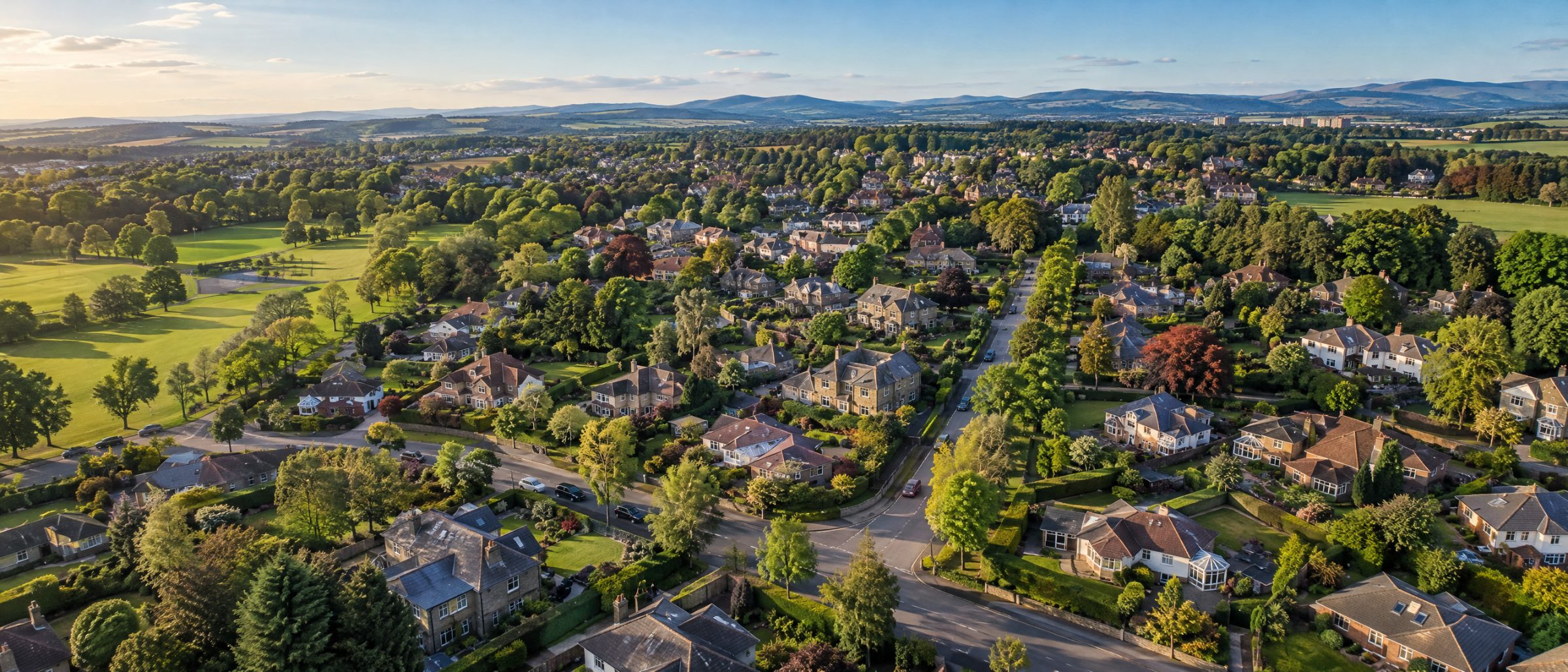 Aerial view of Newton Mearns with detached family homes, gardens and green space