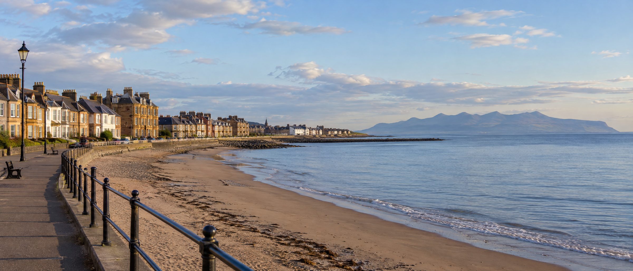 Saltcoats seafront promenade and beach with terraced houses and the Isle of Arran beyond